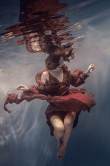 Girl in a red dress under water