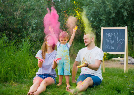 Happy russian family in multi-colored paints playing on summer meadow.
