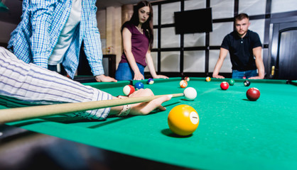 Young man trying to hit the ball in billiard.