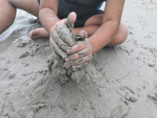  The hands of children playing with sand sculptures on the beach