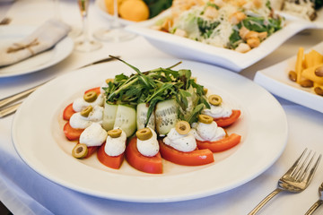 food in a plate on the festive table. table setting at the banquet. cold appetizer and salad for business lunch close up