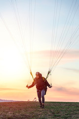Man with paraglider getting ready to fly in sky