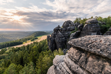 Elbe Sandstone Mountains - View with rocks and wide landscape in the back light, evening light with sunbeams and light clouds, in the foreground sandstone rocks - Germany, Saxony, Saxon Switzerland