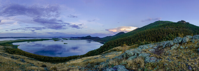 Beautiful mountain lake among mountain ranges and stones green pine forest landscape panoramic