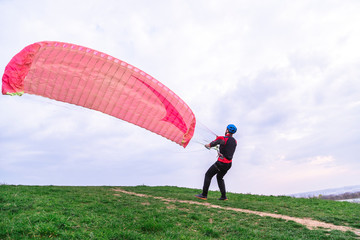 Man lowers paraglider to ground after landing - Powered by Adobe