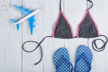 Travel and vacation concept - model of airplane, fashion swimsuit with flip flops in polka dots