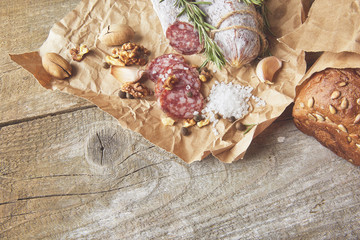 French salami and walnuts on craft paper on wooden background