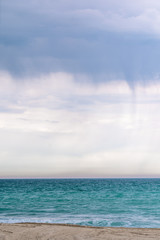 Obraz premium Tropikalna wyspa plaża i morze przy pochmurnej pogodzie. Na morzu dzieje się deszcz