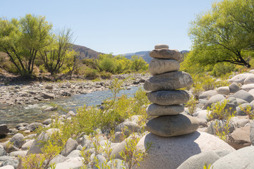 Zen stability concept, relaxation environment, outdoors tranquility, simplicity in nature. Meditation scene next to a river on a soft spring summer sunny day with a pile of stones in perfect balance