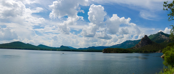 Beautiful mountain lake among mountain ranges and stones green pine forest landscape panoramic