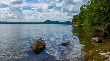Beautiful mountain lake among mountain ranges and stones green pine forest landscape panoramic
