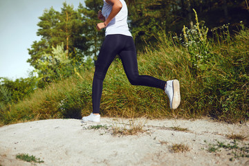 Girl runner runs along in nature in summer.