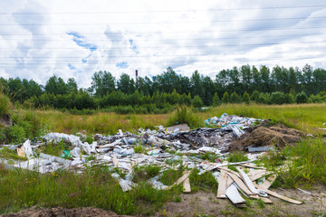 The unauthorized dump of garbage among the wild nature near the industrial and living areas