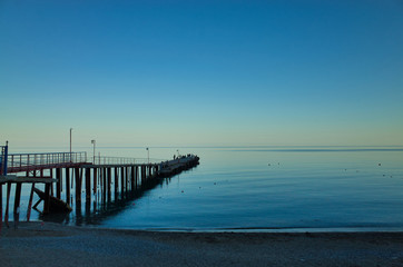 Fototapeta na wymiar Evening in Sudak, the Republic of Crimea. Fishermen on the pier. Black Sea Coast