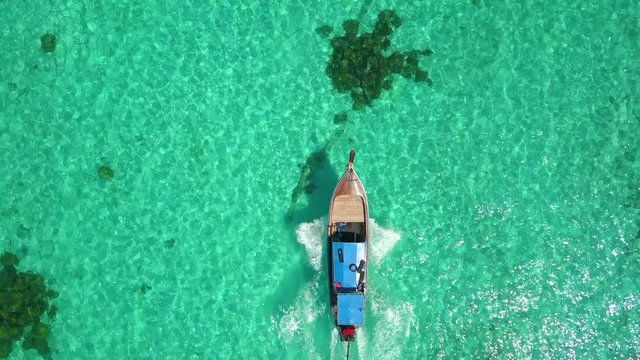 Aerial top view of long-tailed boat is sail on the emerald sea. Calm andaman sea at Koh Lipe, Satun, Thailand. Tracking mode.