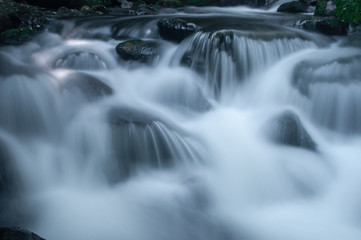 Fototapeta na wymiar Blurred motion of water flowing through river rocks.