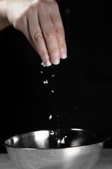 Woman chef sprinkles salt and seasoning for marinated fillet by condiment on a wooden table in the kitchen . Hand sprinkles salt for Preparing healthy food Cooking menu at Home .