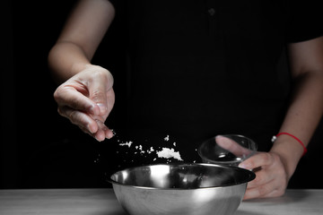 Woman chef sprinkles salt and seasoning for marinated fillet by condiment on a wooden table in the kitchen . Hand sprinkles salt for Preparing healthy food Cooking menu at Home .