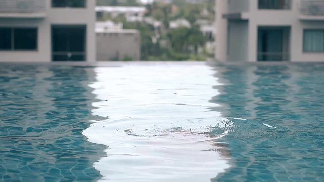 athletic brunette lady swims and dives in empty hotel pool on building roof at gentle sunlight slow motion
