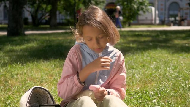 girl plays with slime on the park bench. the blue stretching slime In the hands of the little girl