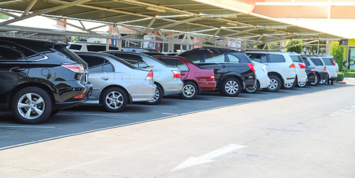 Closeup Of Rear, Back Side Of Black Car With Other Cars Parking In Parking Lot Under Roof In Bright Sunny Day.