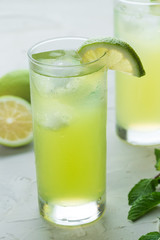 mojito cocktail refreshing summer drink on a white textured surface with lime and mint leafs 