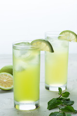 mojito cocktail refreshing summer drink on a white textured surface with lime and mint leafs 