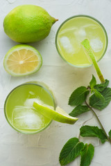 mojito cocktail refreshing summer drink on a white textured surface with lime and mint leafs 