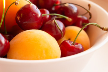 cherries and apricots in a white plate