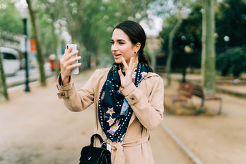 Attractive woman having a video call on a mobile phone in the street