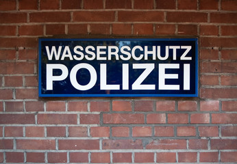 Fototapeta premium Düsseldorf 2019: Sign from the river Police at media harbour Dusseldorf in front of red brick wall. The sign says 