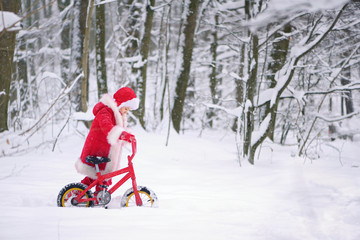 Fototapeta na wymiar Child dressed as Santa Claus with gifts in snowy winter outdoors.