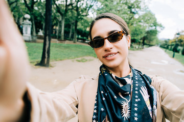 Smiling young girl making selfie photo in park