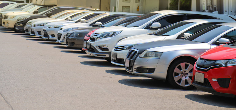 Closeup of front side of  cars parking in outdoor parking lot beside the street in bright sunny day. 