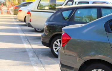 Fototapeta premium Closeup of rear side of blue car with other cars parking in parking area beside the street in bright sunny day. 