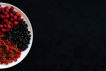 Juicy ripe berries in a plate on a black background. Berry pizza. Sector of berries on a plate. Ripe fresh berries on a black background.