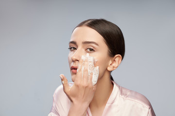 Beautiful young woman washing face with foaming cleanser