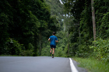 Asian man are running training in roads with forests.