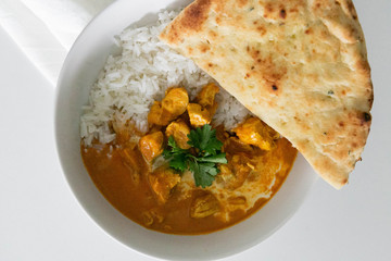 Bowl of Indian Butter Chicken with Jasmine Rice, Homemade Naan, and Cilantro, White Background, Closeup