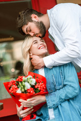 Happy woman turning to her boyfriend after getting flowers from him