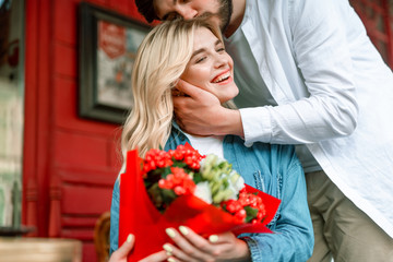 Smiling lady near boyfriend after getting flowers from him