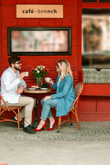 Obraz premium Happy couple sitting at table with desserts and coffee outdoors