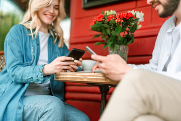 Happy couple with mobile typing in cafe outdoors