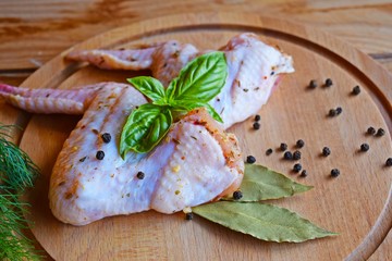 Raw chicken wings with spices and herbs on a wooden Board for grilling.