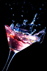 A martini glass with green olives on a black background