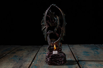 Low key still life candlestick two dragons and fired candle on wooden textured and old scratch table