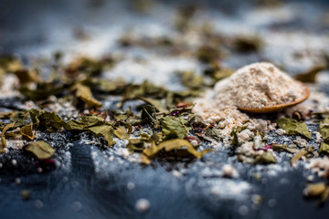 Neem or Indian Lilac face mask on the black wooden surface for acne and scars consisting of gram flour, neem paste, and some curd.