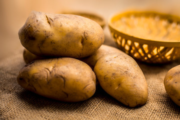 Close up shot of potato or aloo or alu on jute bag surface along with two vegetable and fruit...