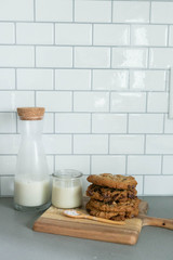 Stack of Homemade Salted Chocolate Chip Cookies with glass of milk, White Subway Tile Background, Wooden Plate
