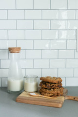 Stack of Homemade Salted Chocolate Chip Cookies with glass of milk, White Subway Tile Background, Wooden Plate